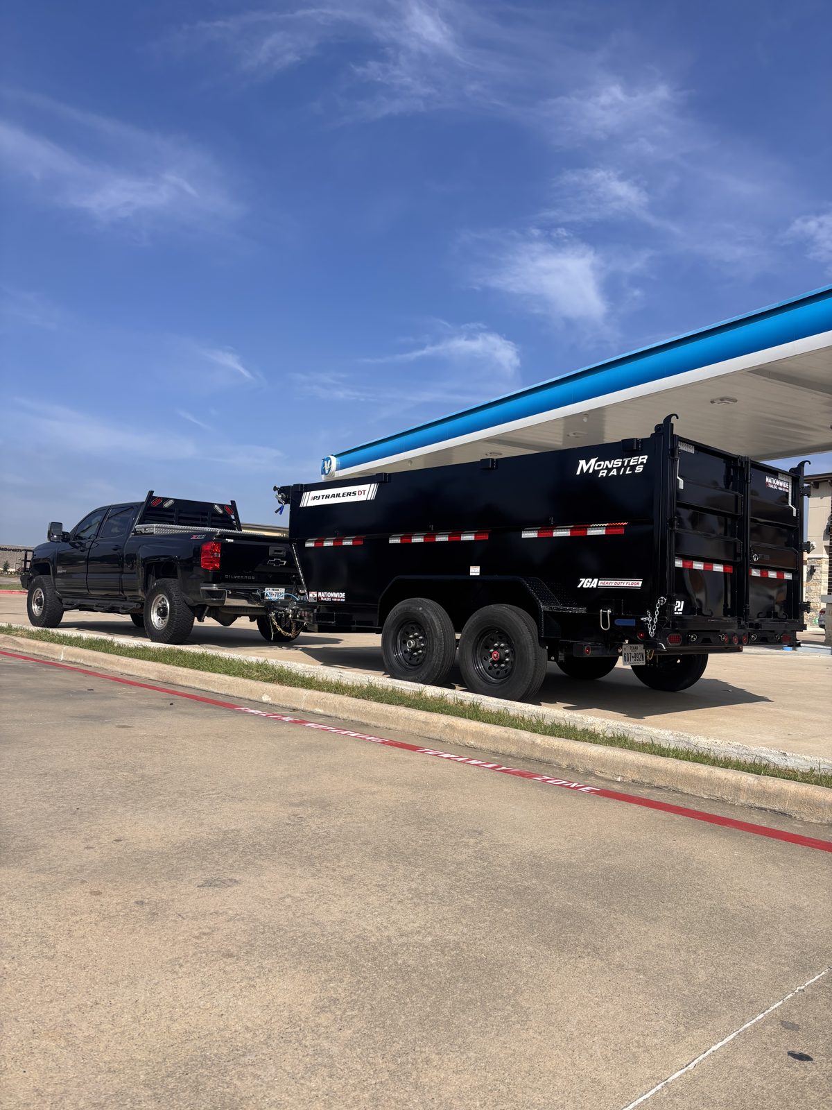 Dump Hero's black dump trailer hitched to a pickup truck